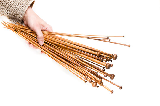 Woman hand holding a lot wooden knitting needles on white background