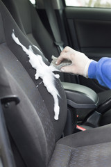 Ręczne pranie tapicerki samochodowej za pomocą pianki do prania i gąbki. Ręczne szorowanie oparcia fotela samochodu osobowego.