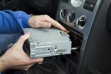Mechanik wkłada radio samochodowe do kieszeni na radio w samochodzie. Podłączanie radia. - obrazy, fototapety, plakaty