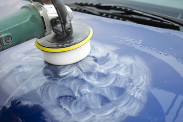 Polerowanie lakieru na masce samochodu za pomocą polerki elektrycznej.