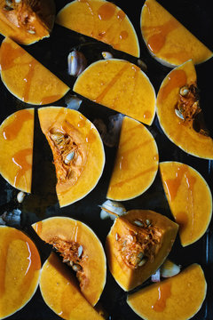 Raw slices of butternut squash with garlic and chili oil on an oven tray