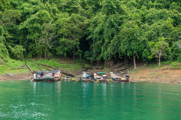 Longtail boats floating on the emerald green waters of Cheow Lan Lake