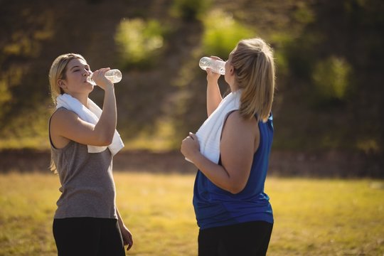 Friends drinking water after workout during obstacle course