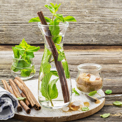 Cold refreshing Moroccan tea with cinnamon and mint in a tall decanter on a simple wooden...