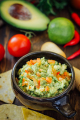 Guacamole with corn chips - nachos, made from avocado, tomatoes and lime.
