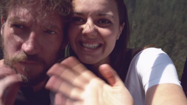Happy couple in cableway in mountains making video phone call showing to friends the view smiling
