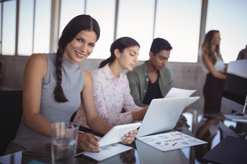 Portrait of young woman working with colleagues 