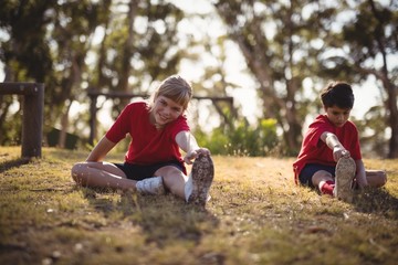 Happy kids performing stretching exercise during obstacle course