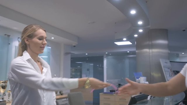 The girl gives the card and the keys from the sauna to the young man