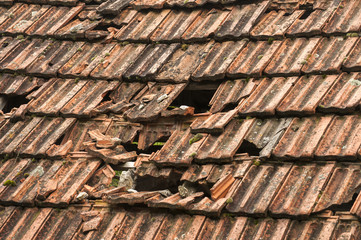 Part of roof of vintage house with broken and fallen ceramic tiles
