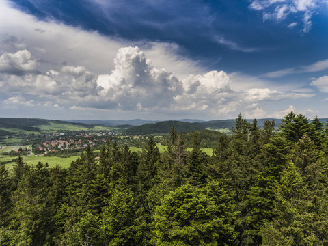 Aerial view of the summer time in mountains near Stronie Slaskie town in Poland. Pine tree forest and clouds over blue sky. View from above.
