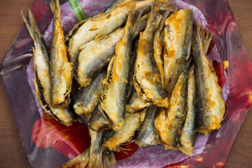 Fried baltic herring on a plate on wooden background