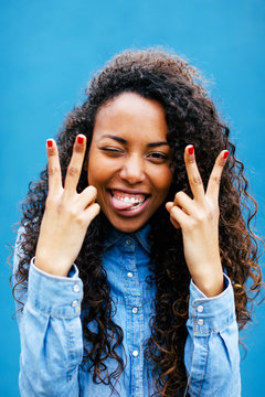 Young african woman doing victory sign in front of a blue wall