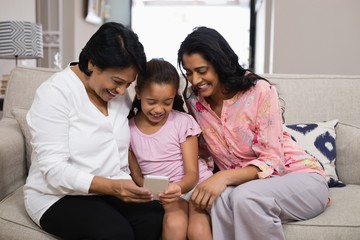 Happy multi-generation family using mobile phone 