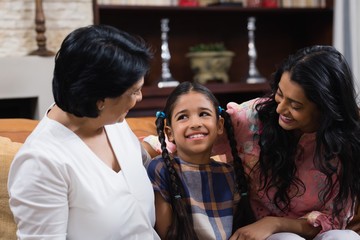 Cute smiling girl with mother and grandmother sitting at home