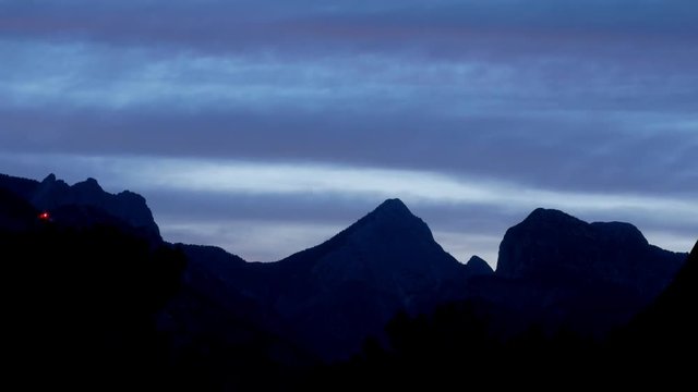 The night falls in a mountain valley. The clouds change color from multicolored to dark. TimeLapse