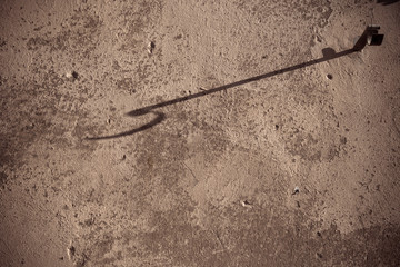 Shadow of an hook on a wall at sunset light