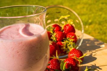 Sweet strawberry milkshake in the garden with strawberry on wood table