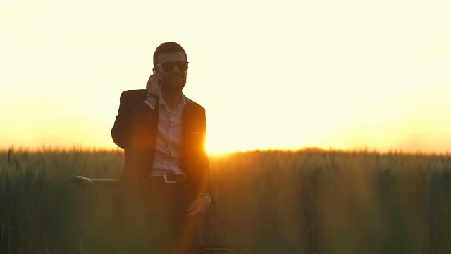 Positive man in suite and glasses talk phone field with bicycle dawn slow motion