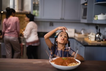 Girl eating spaghetti in kitchen