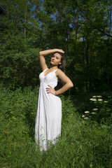 Young girl with white dress posing in a grass field