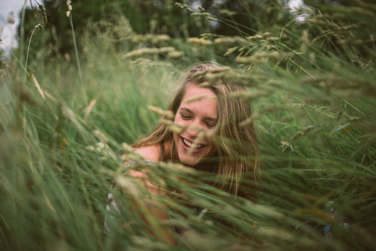 A young attractive woman cracks a smile through the tall grass