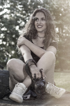 Portrait of a beautiful female photographer with a professional camera. Woman photographer with a professional camera and bag. Vintage style photo.