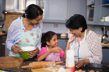 Girl with mother and grandmother preparing food 
