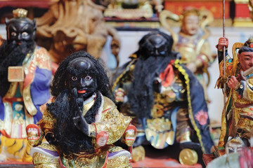 Various Thai souvenirs for sale at night market, Rambuttri Alley, Bangkok, Thailand. Statues of Chinese warriors in colorful outfits. Soft selective focus