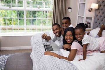 Portrait of smiling family shopping online on bed