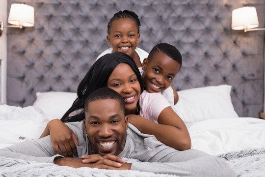 Portrait of smiling family lying on bed