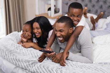 Happy family watching television while lying on bed
