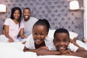 Siblings lying on bed with parents sitting 