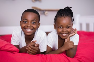 Portrait of siblings lying together on bed