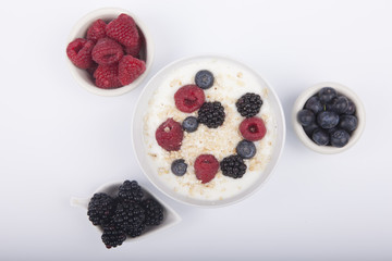 bowl of white yogurt with berries and oat flakes isolated