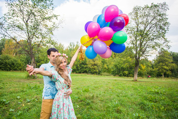 Young couple having weekend and walking with balloons on nature