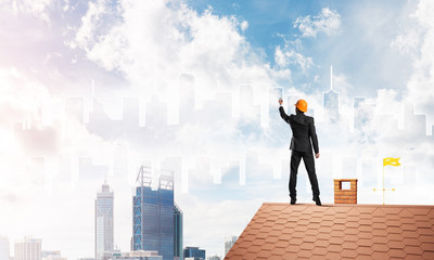 Man architect draw silhouette of modern city on blue sky. Mixed media