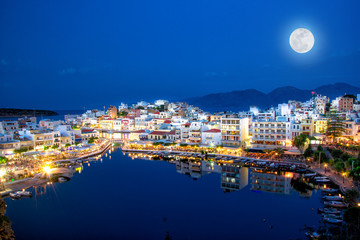 The lake Voulismeni in Agios Nikolaos at night with fullmoon, a picturesque coastal town with...