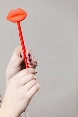 Happy woman holding fake lips on stick