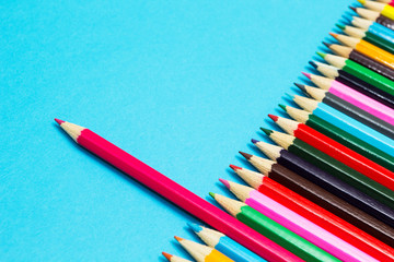 Bright abstract background of multicolored pencils on a blue background, top view. Space for text.