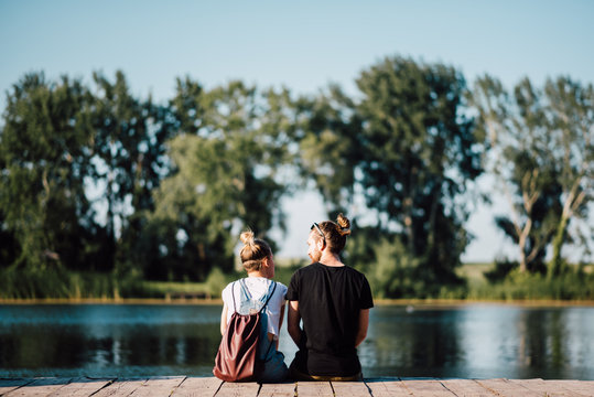 Couple sitting on the wooden dock by the lake 