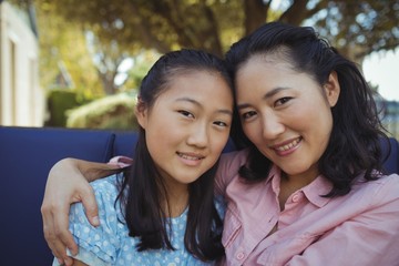 Mother and daughter relaxing on couch outside home