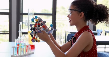 Portrait of happy schoolgirl experimenting molecule model in laboratory - Powered by Adobe