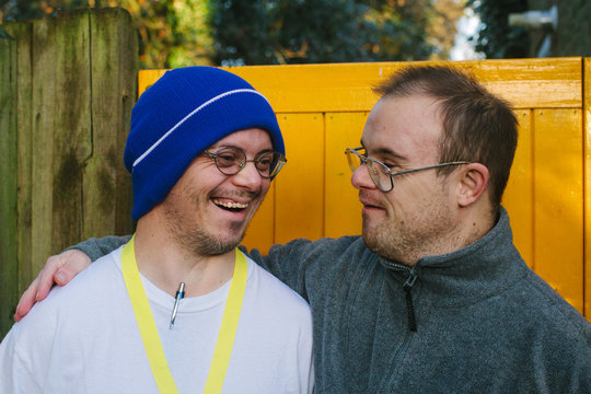 Two men with Down's Syndrome with their arms around each other share a joke