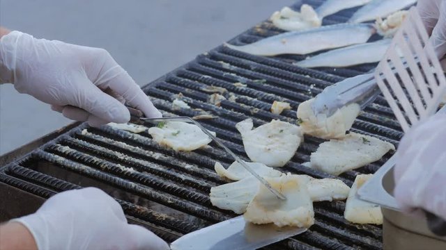 The chef toils over an open grill frying fish, rapans and squid. Cooking mackerel fillet at grill for fish durum.