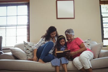 Mother and daughter reading book in living room