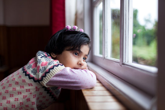 Little girl in a contemplative mood sitting by the window
