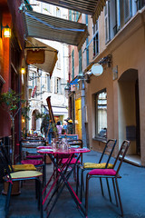 Restaurant in a alley of historic center of Nice, with tables and chairs outdoor, France