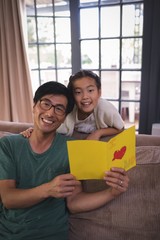 Obraz premium Father and daughter holding greeting card in living room