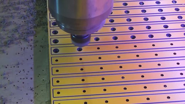 The CNC milling machine reamers the holes in the plastic sheet. Cone milling cutter.